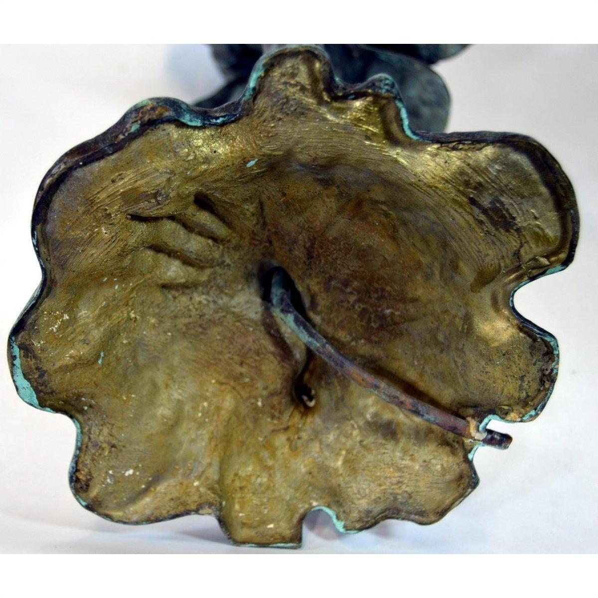 Close-up of green and gold bronze frog sculpture with textured finish and metal stem, lost wax technique.