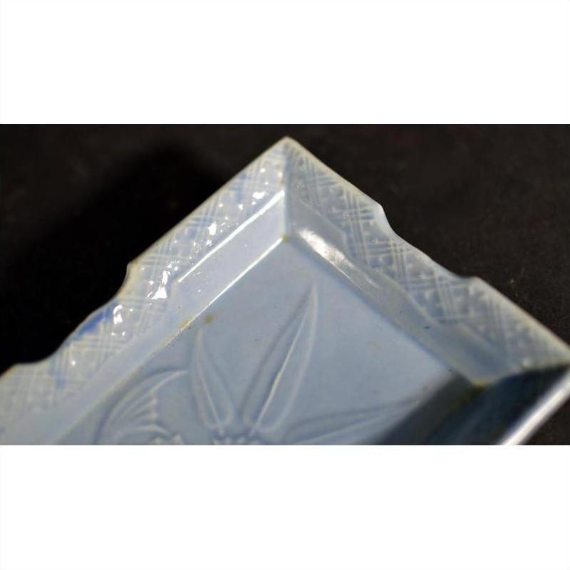Close-up of a blue and white porcelain dish with hand painted floral and geometric patterns along rim and base.