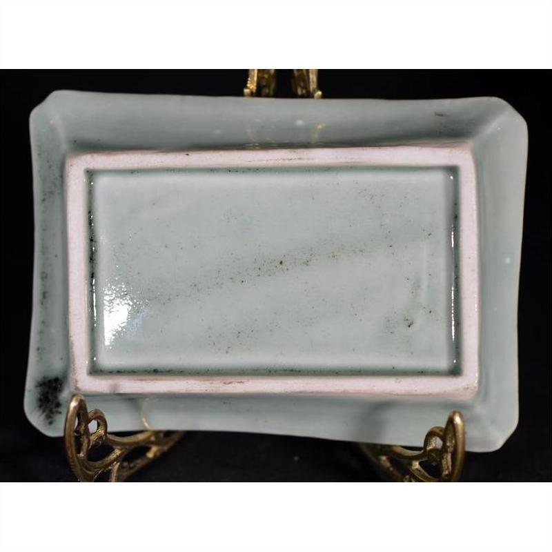 White and multicolor hand-painted porcelain rectangular dish with slightly raised edges, bottom view.