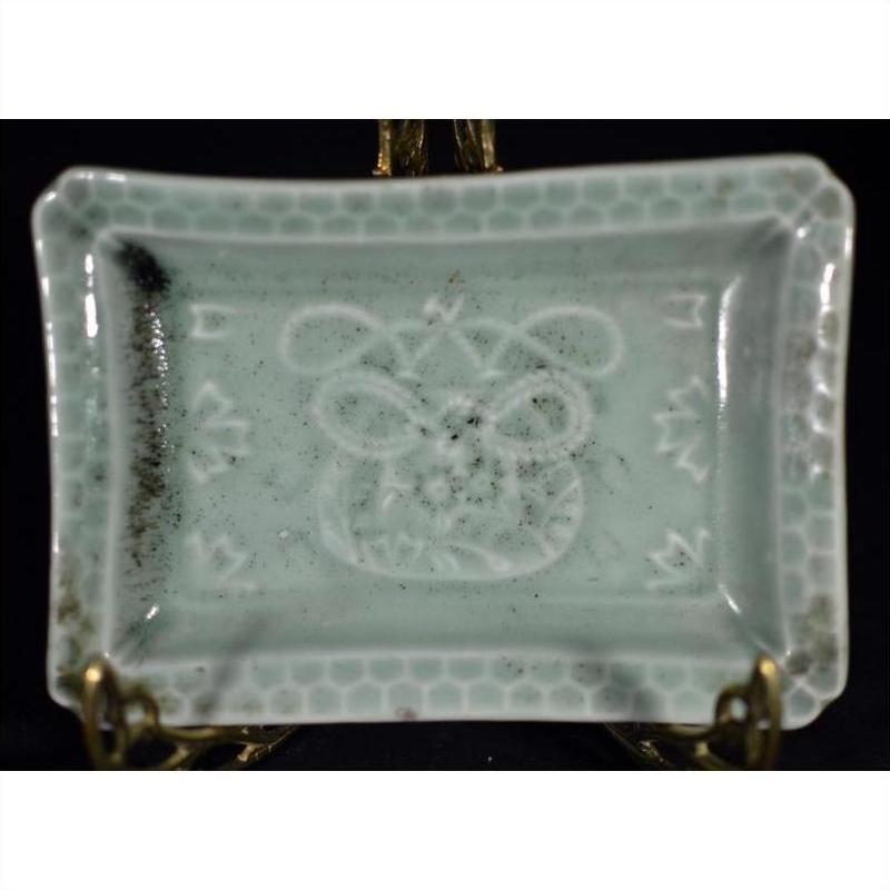 Light blue-green porcelain dish with hand painted geometric border and abstract floral motifs, close-up view.