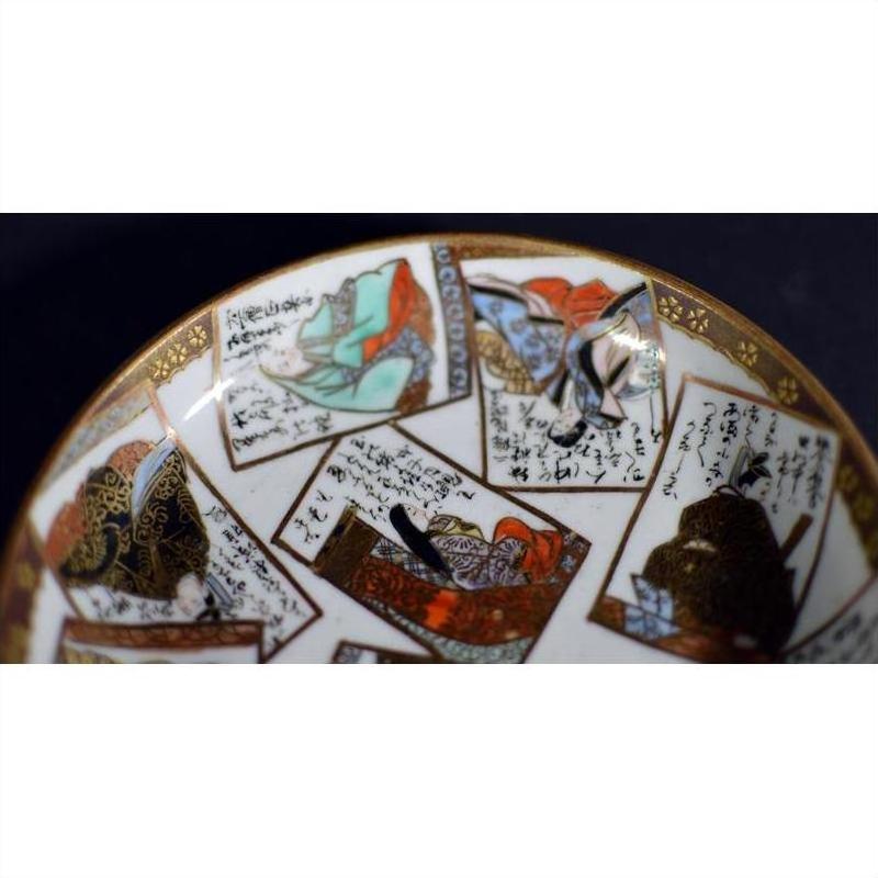 Close-up of vintage hand painted porcelain plate with Japanese artwork and calligraphy on a dark background.