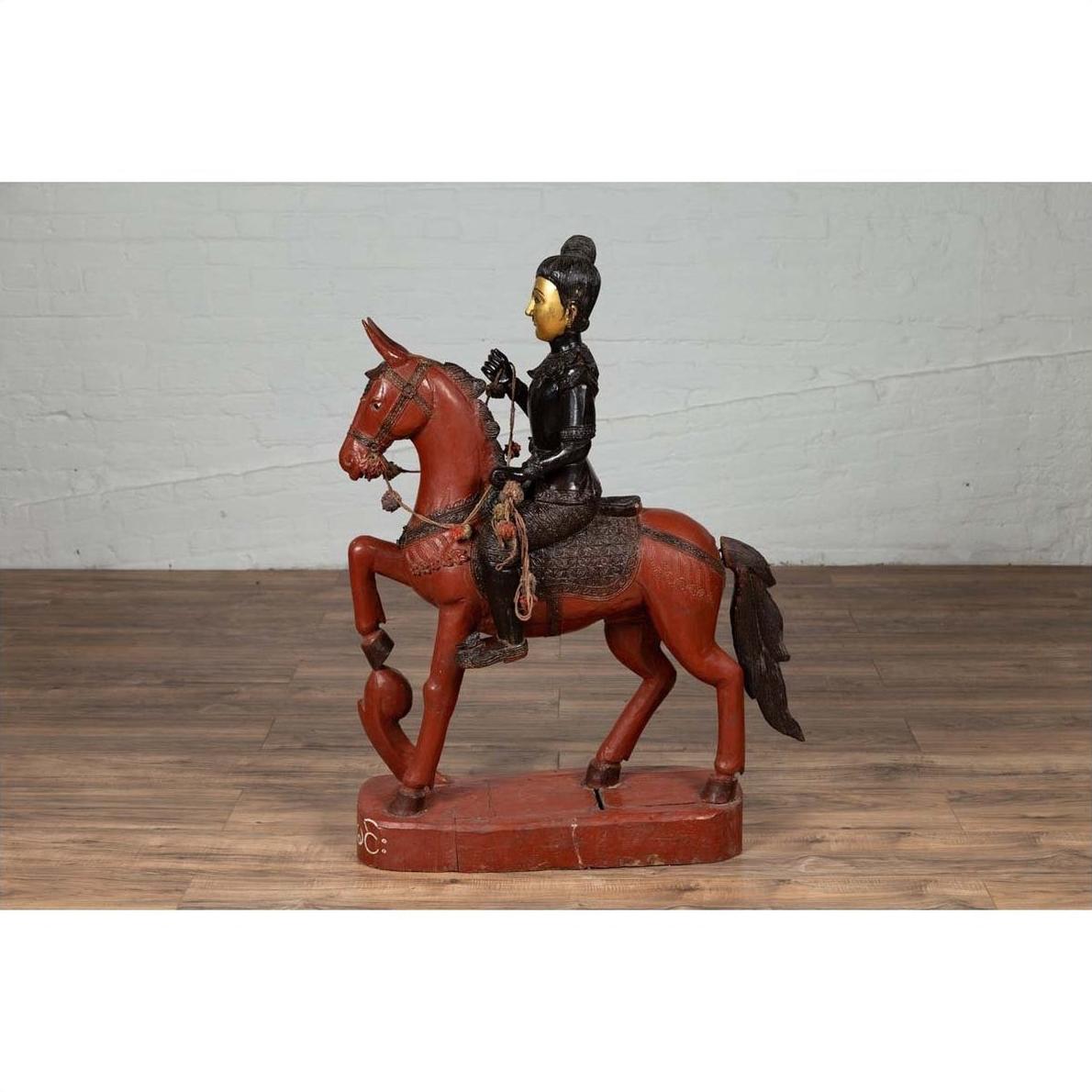 Polychrome wooden Burmese warrior on horseback statue, vintage style, displayed on wooden floor.