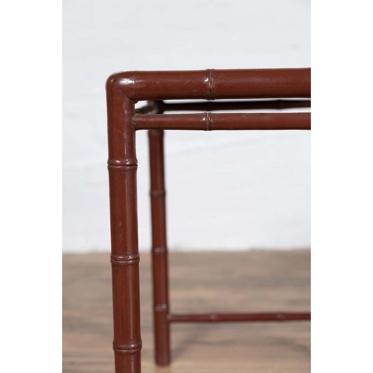 Close-up of brown bamboo table leg with patina, on wooden floor.