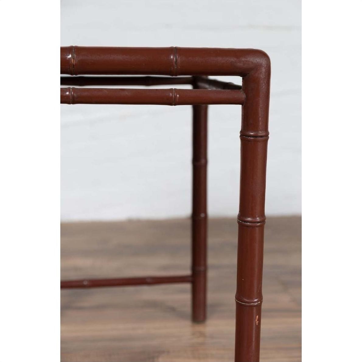 Close-up of brown bamboo table legs with patina on wood floor against a white wall.