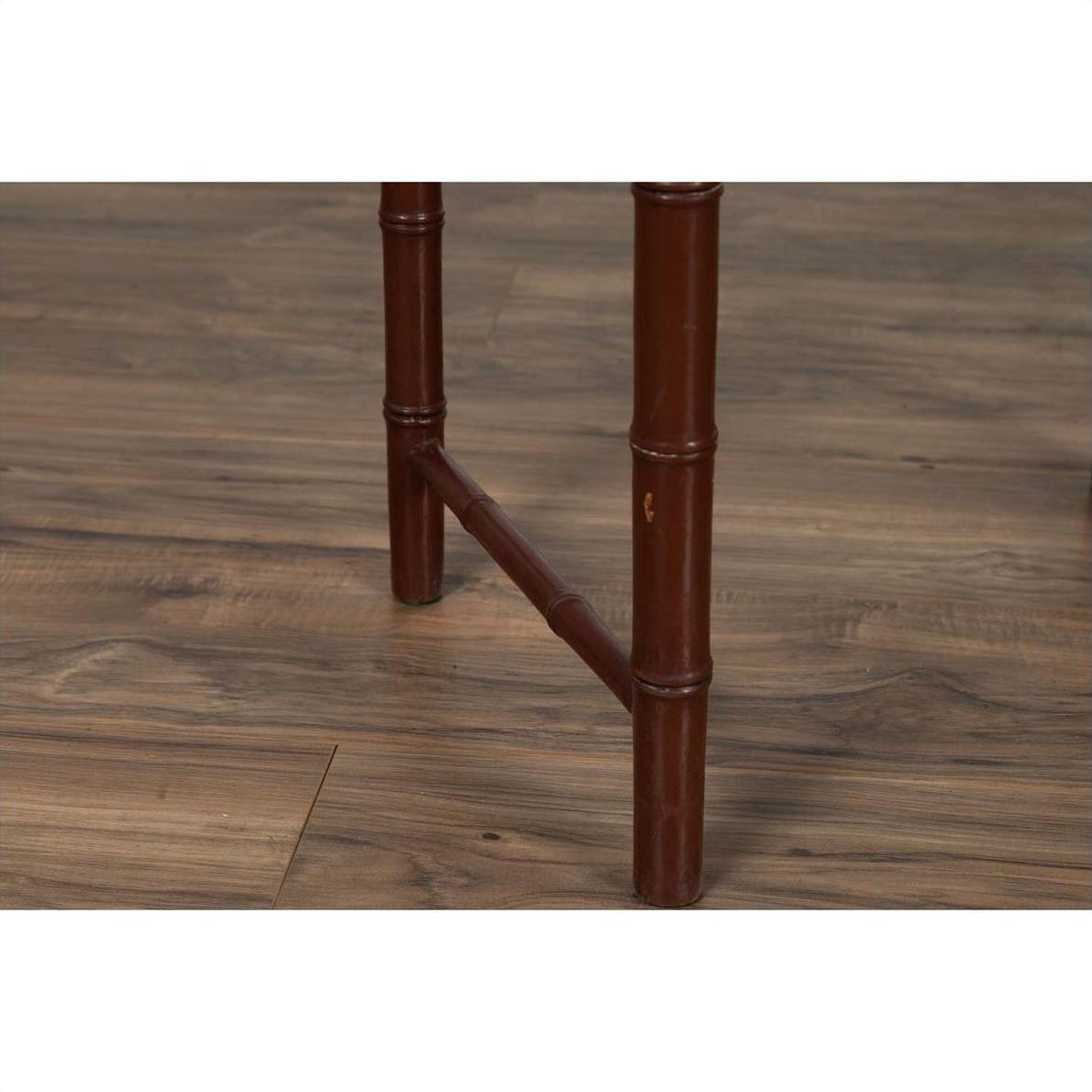 Close-up of two brown bamboo table legs with brownish patina on a wooden floor.