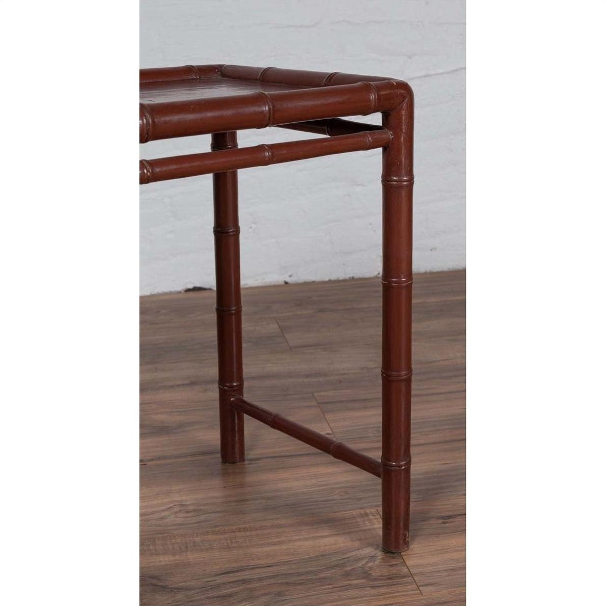 Close-up of brown bamboo table leg with aged patina, on wood floor next to white brick wall.
