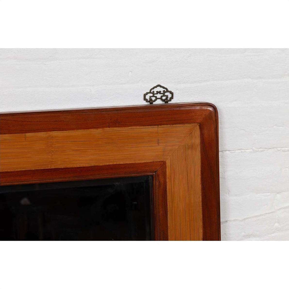 Close-up of a brown elm and rattan square mirror with beveled glass, hanging on a white wall.