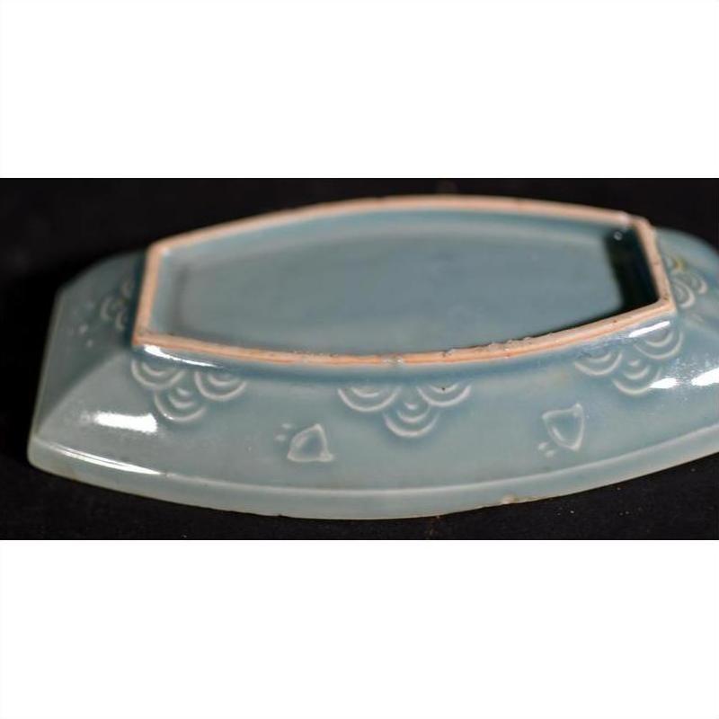 Light blue celadon ceramic dish with rectangular opening and embossed cloud patterns, side view.