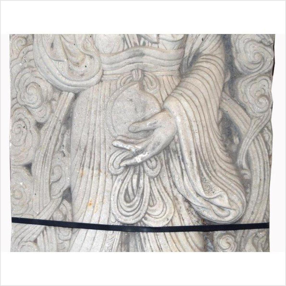 Close-up of white stone hand-carved Chinese Bodhisattva sculpture showing detailed hand and robe carving.