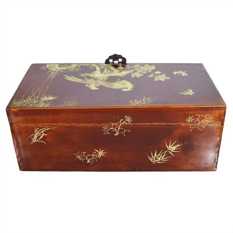 Black lacquered wooden dowry box with gold floral designs and a decorative handle on the lid, shown indoors.