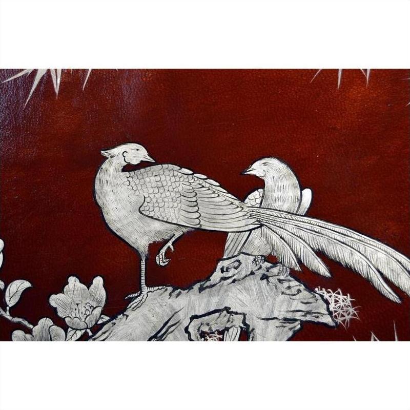 Close-up of a dark red lacquered dowry box with hand painted silver-engraved birds and flowers.
