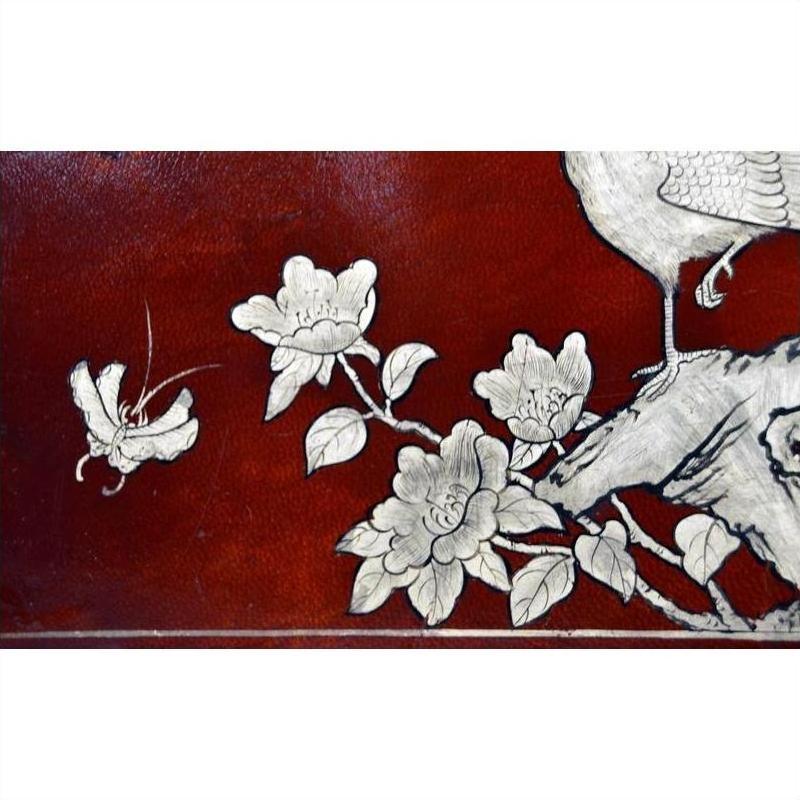 Dark red lacquered Chinese dowry box with hand painted white floral, butterfly, and bird design, close-up view.