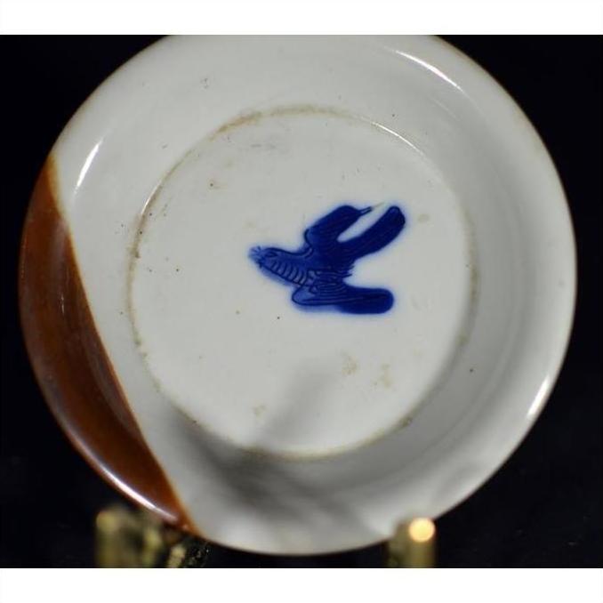 White porcelain dish with hand painted blue bird motif, brown rim, close-up.