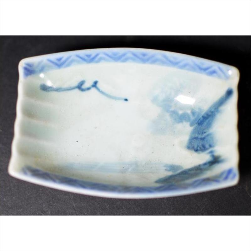 Blue and white porcelain dish with hand painted blue designs and geometric border, vintage style, close-up view.