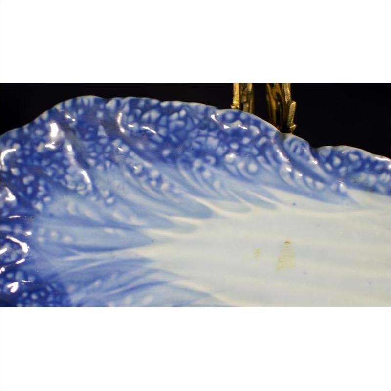 Close-up of blue and white hand-painted porcelain dish with textured wavy edge and gradient detailing.