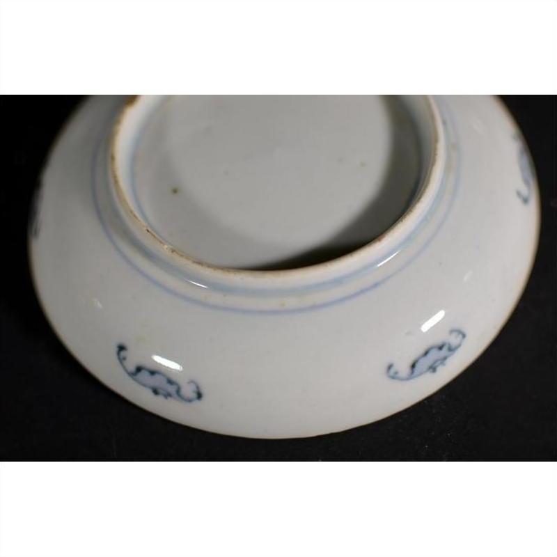 Close-up of underside of vintage Chinese porcelain plate with small blue decorative patterns near base.
