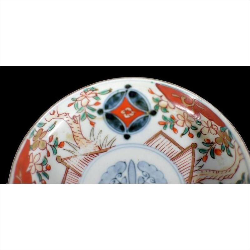 Close-up of a vintage Chinese porcelain plate with vibrant red, green, and blue hand-painted floral patterns.