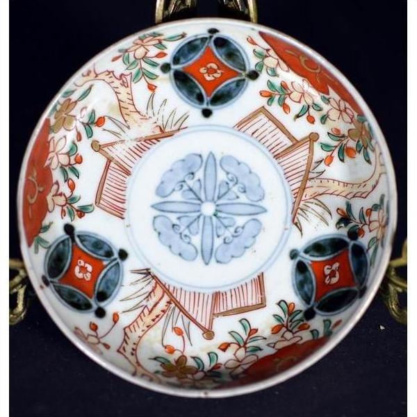 Close-up of a vintage Chinese porcelain plate with red, green, and orange floral and geometric designs on white.