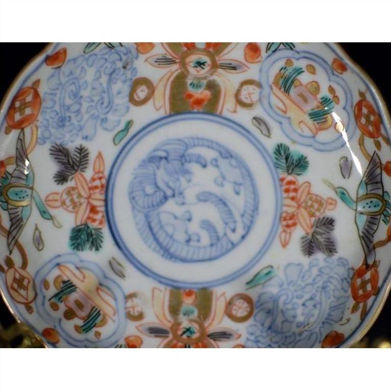 Close-up of vintage Chinese porcelain plate with blue, red, and gold floral and abstract patterns on white background.
