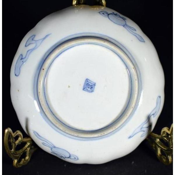 White and blue porcelain plate bottom with square mark, displayed on a gold stand.