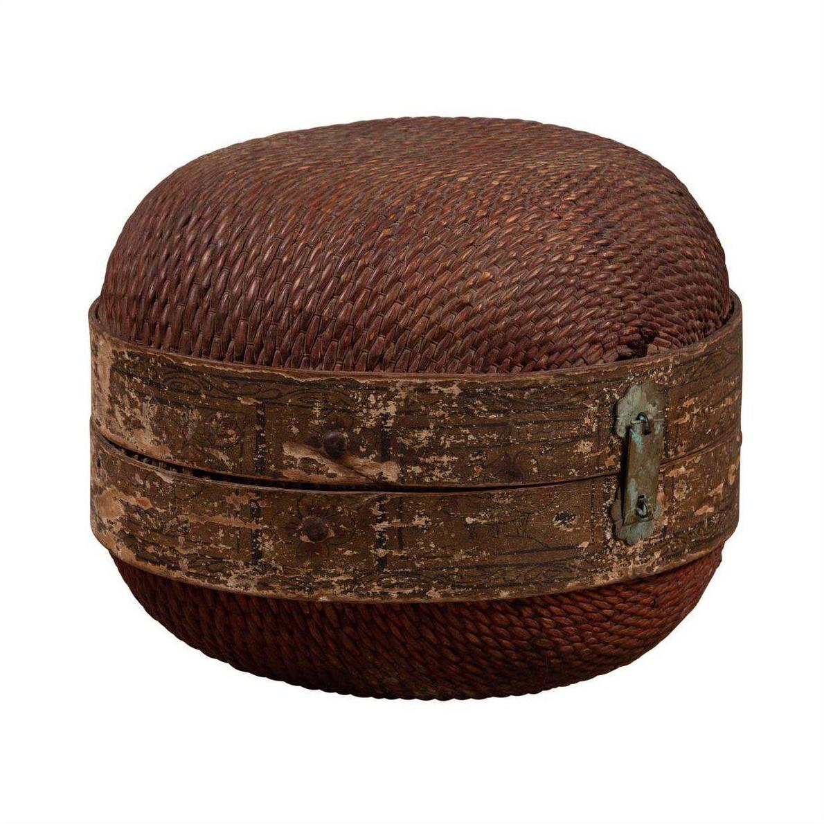 Brown rattan circular hat box with weathered patina on white background.