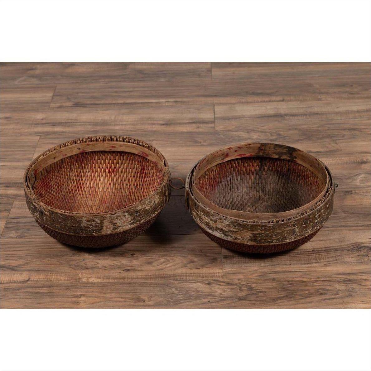 Brown rattan hat boxes with weathered patina, vintage Chinese mid-century style, side by side on wooden floor indoors.