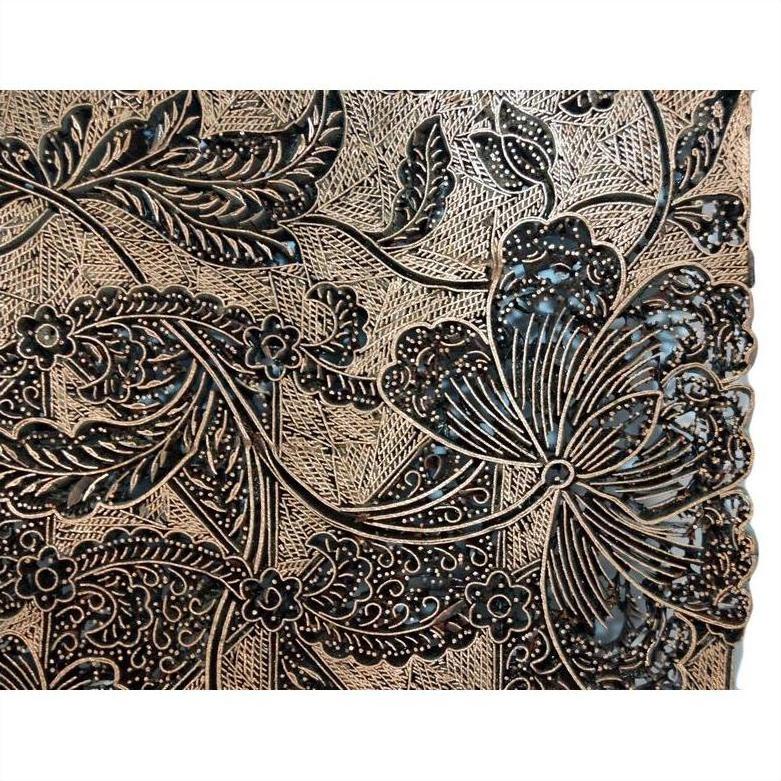 Close-up of vintage copper Batek ink block with detailed floral and leaf carvings, showing intricate botanical textures.