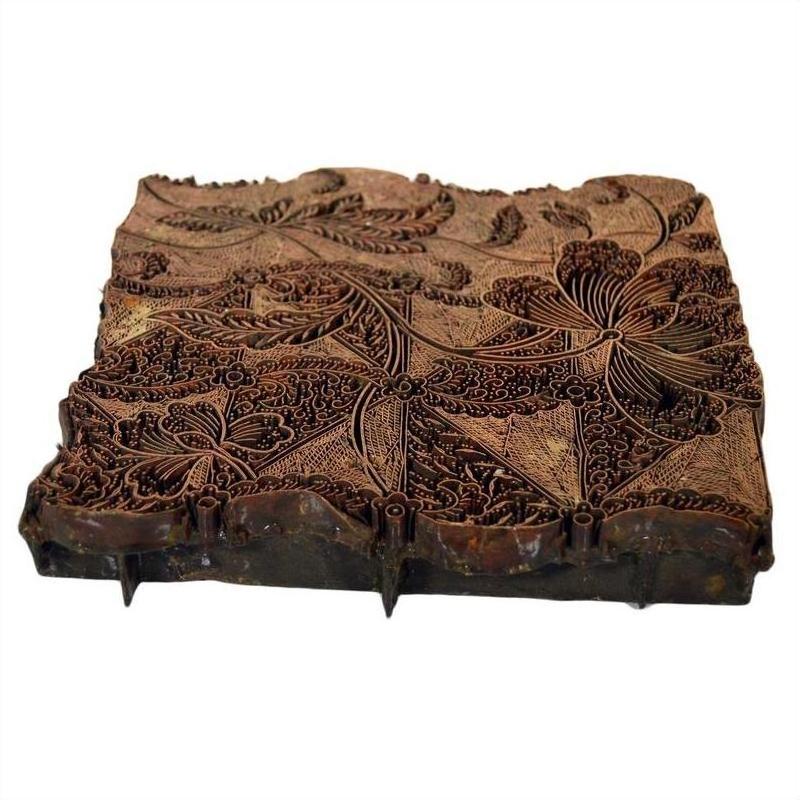 Close-up of vintage copper Batek ink block with intricate floral and leaf patterns carved on rectangular surface.