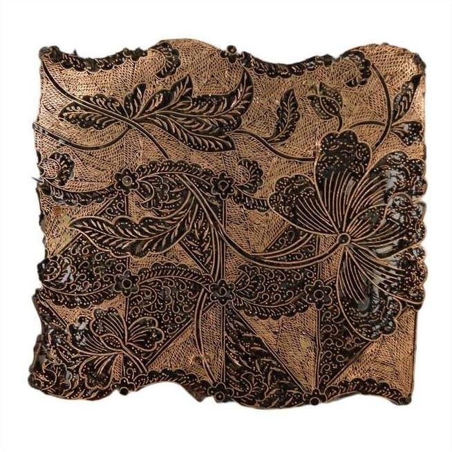 Close-up of vintage copper Batek ink block with engraved intricate floral and leaf patterns.