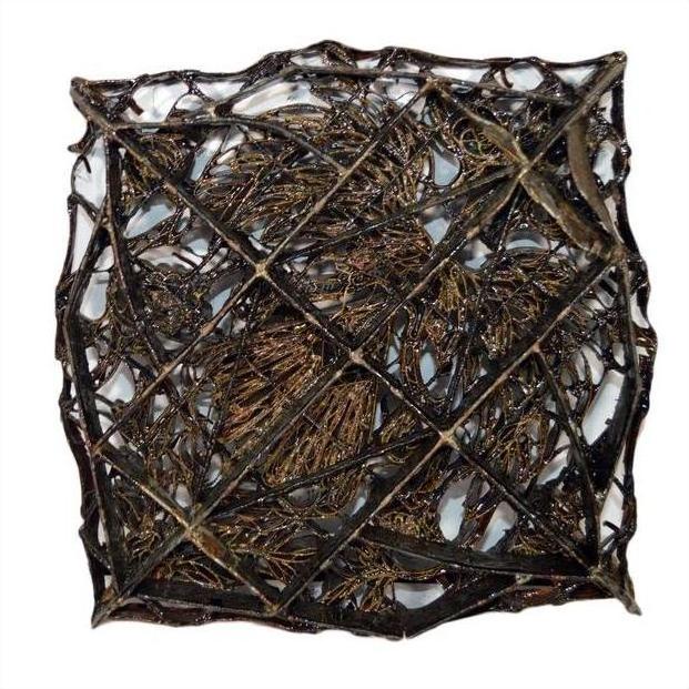 Close-up of a vintage copper batik ink block with intersecting lines and organic shapes in a square frame.