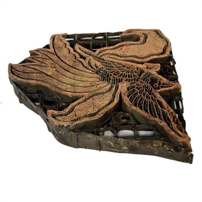 Close-up of vintage copper Batek ink block with intricate bird design, used for textile printing.