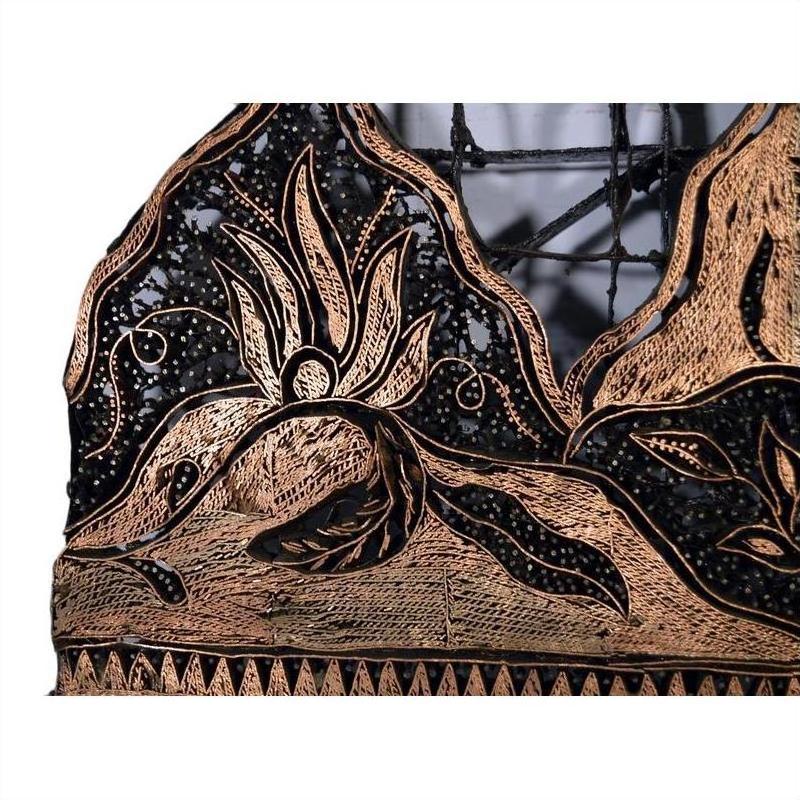 Close-up of vintage copper Batek ink block with ornate abstract animal and leaf motifs.