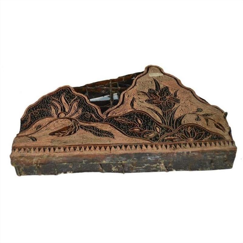 Close-up of vintage copper Batek ink block stamp with intricate floral patterns, used in textile design.