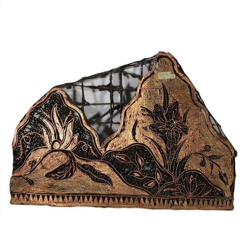 Close-up of a vintage copper Batek ink block with floral motifs on a black mesh background.