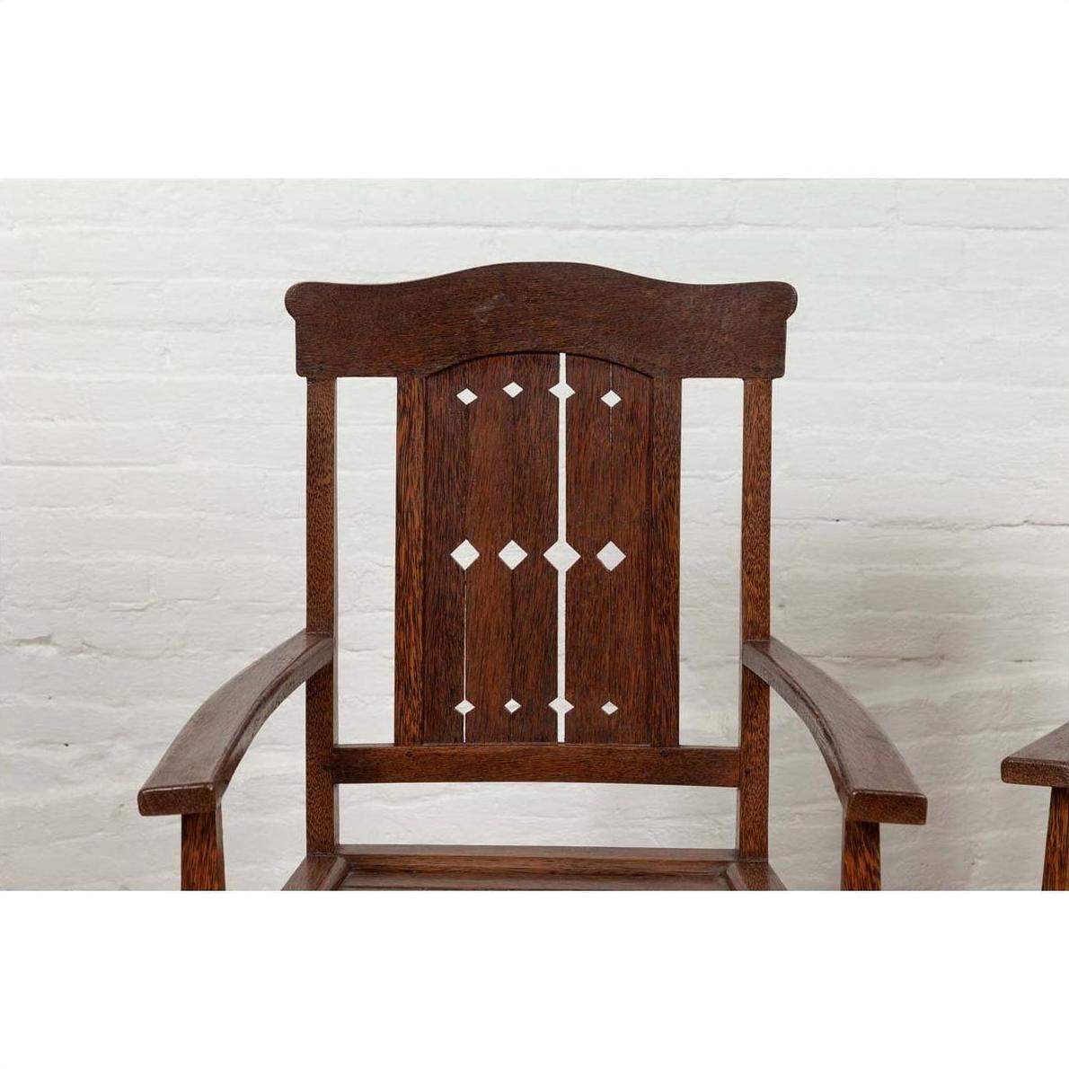 Brown wood armchair with pierced slats and bonnet-style rail, Dutch Colonial style, indoor setting.