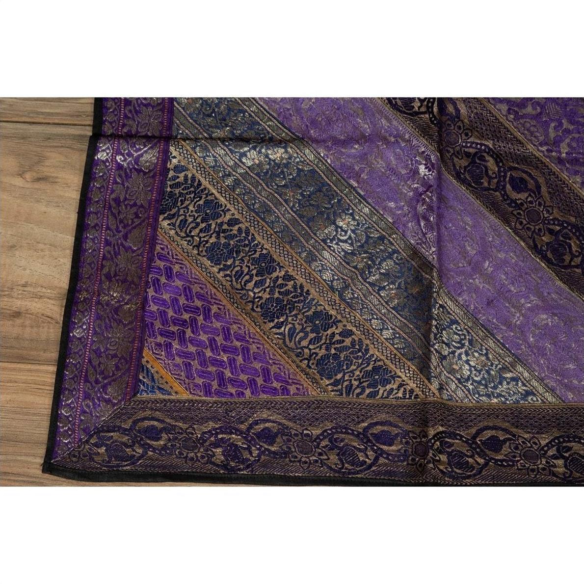 Purple silk fabric with silver and gold embroidery on a wooden surface.