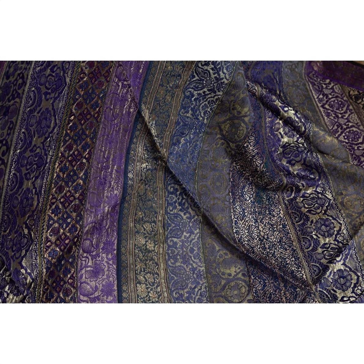 Close-up of purple silk fabric with silver and gold embroidery, showing intricate designs.