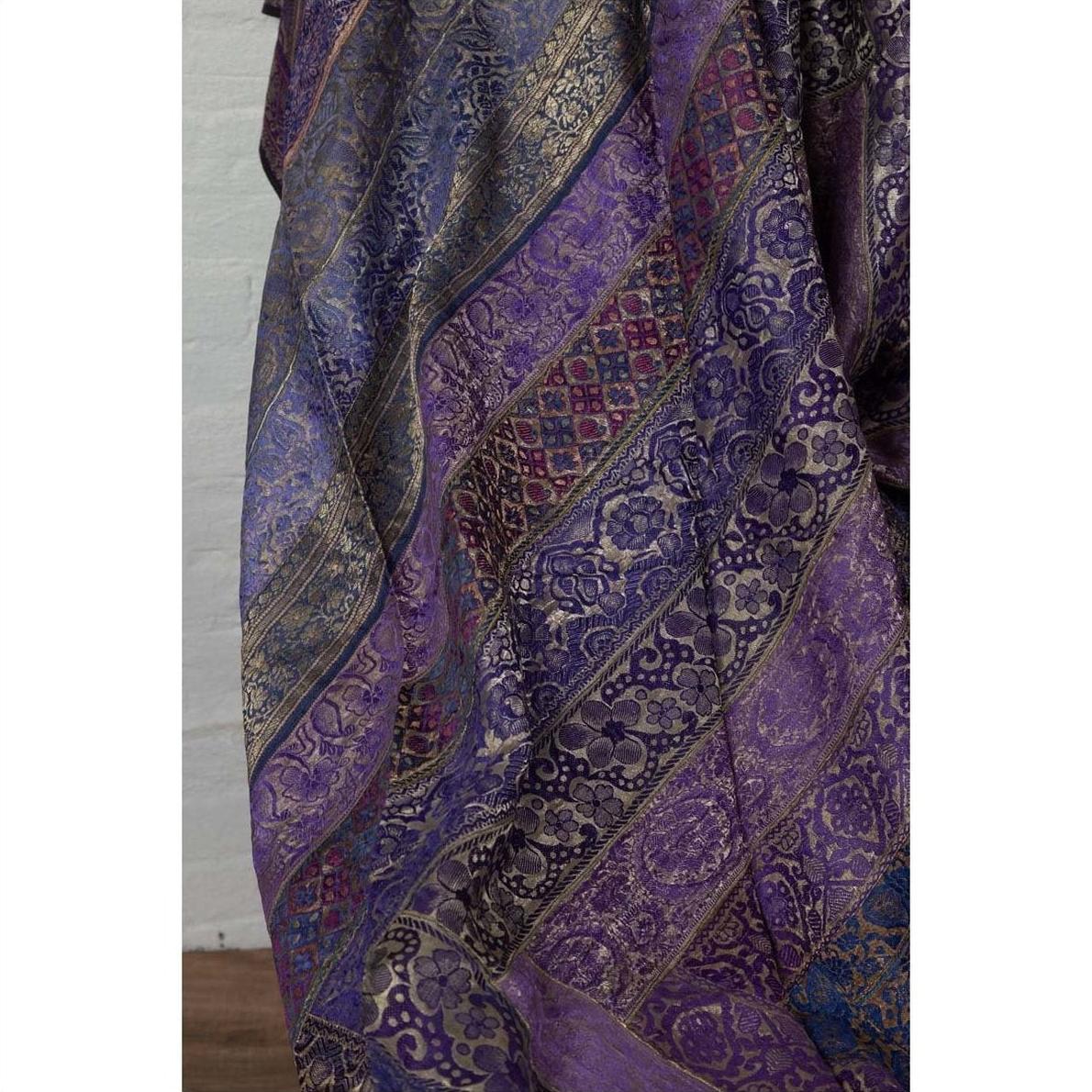 Purple silk fabric with silver and gold embroidery in floral and geometric patterns, close-up.