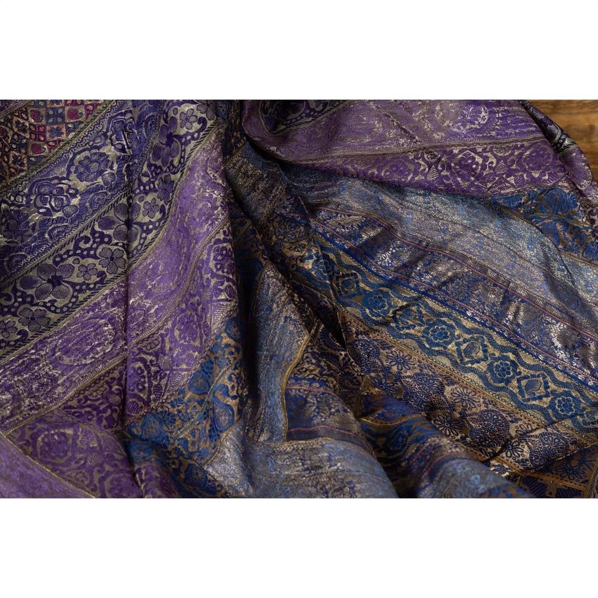 Purple silk fabric with gold and silver embroidery, draped in soft folds, close-up.