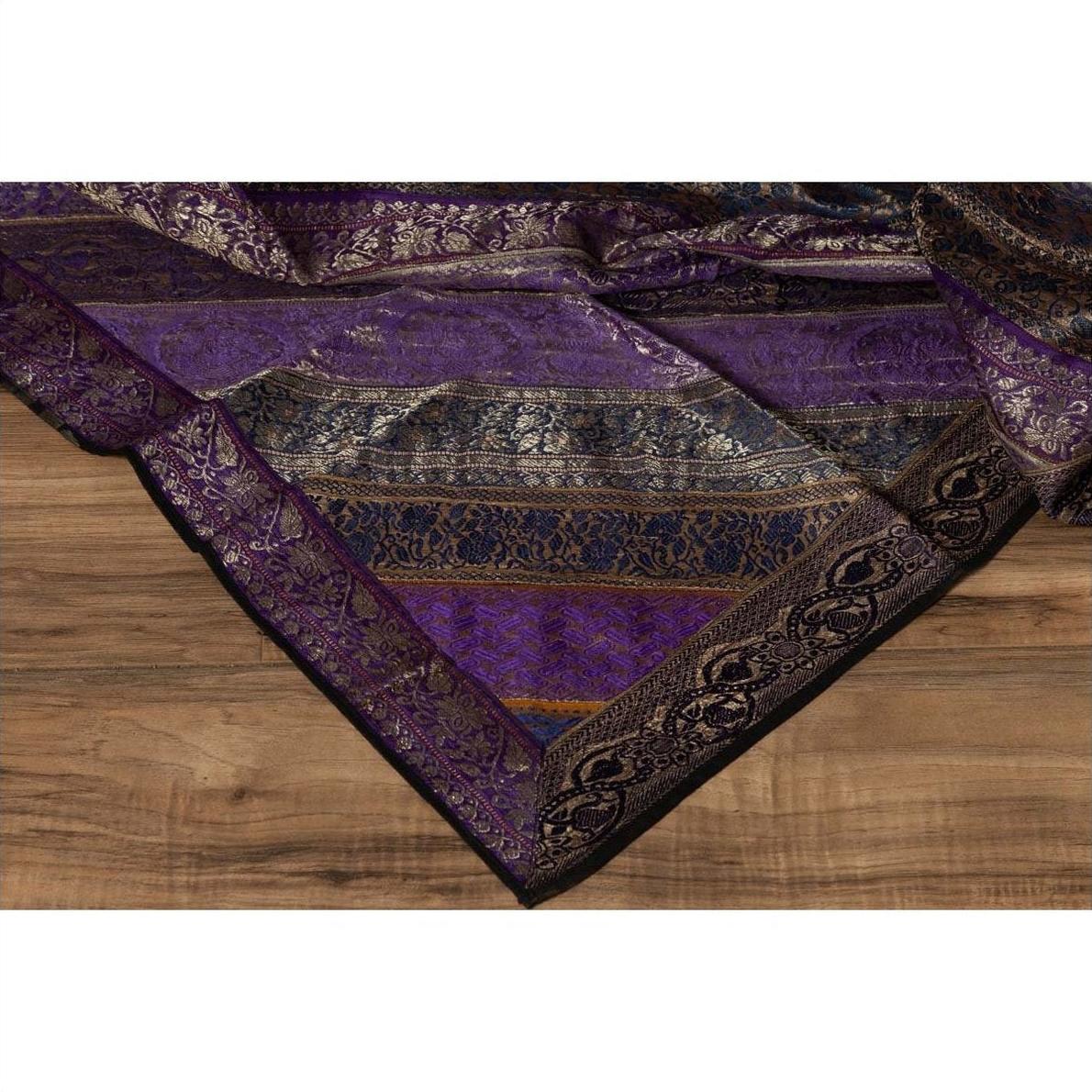 Purple silk fabric with silver and gold embroidery accents on a wooden surface.
