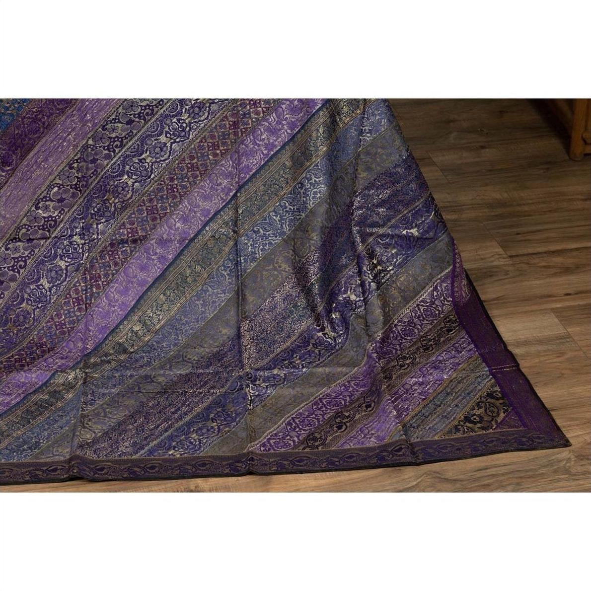 Purple silk fabric with purple, silver, and gold embroidery on a wooden floor.