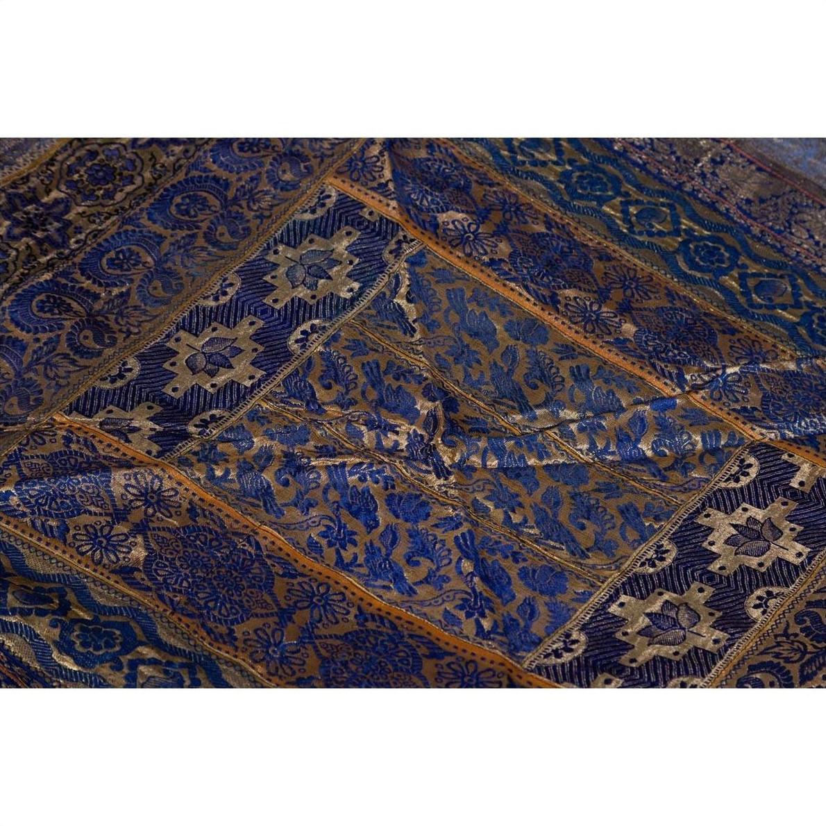 Purple silk fabric with embroidered floral and geometric designs in purple, silver, and gold tones, close-up.