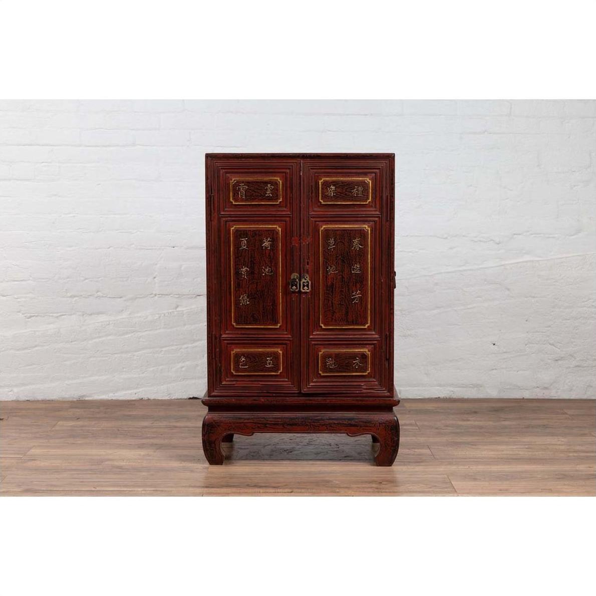 Red lacquered wood display cabinet with gold calligraphy on a wooden floor indoors.