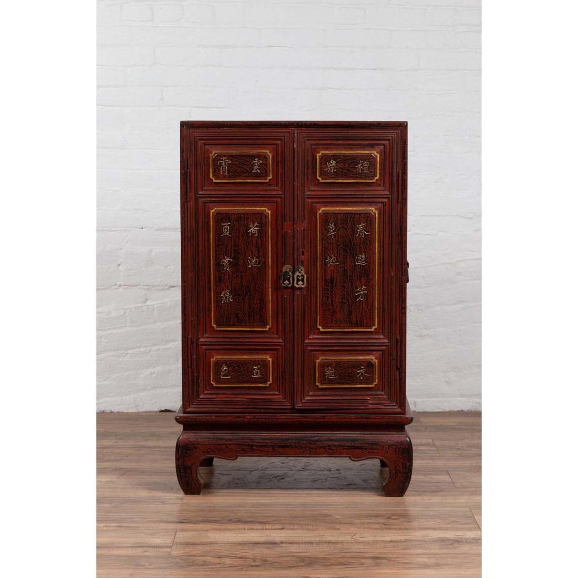 Red Negora lacquer and wood Japanese display cabinet with gilded calligraphy on a wooden floor by a white wall.
