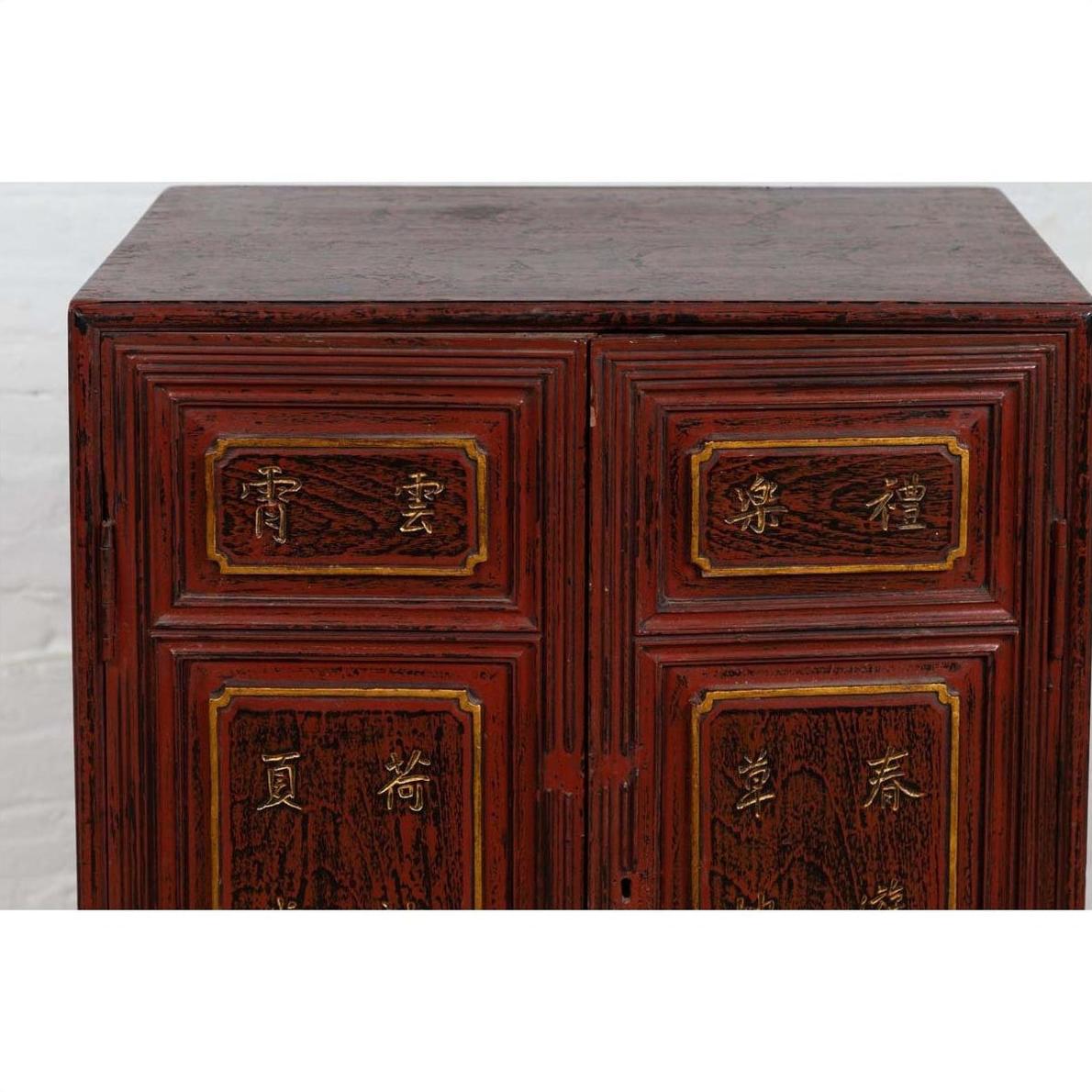 Close-up of red Negora lacquer display cabinet with gilded calligraphy on panels, vintage Japanese style.