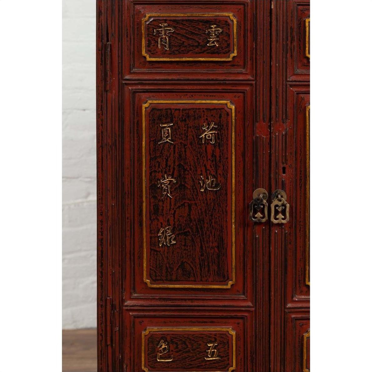 Close-up of red lacquered Japanese display cabinet with metal handles and gold calligraphy detailing.