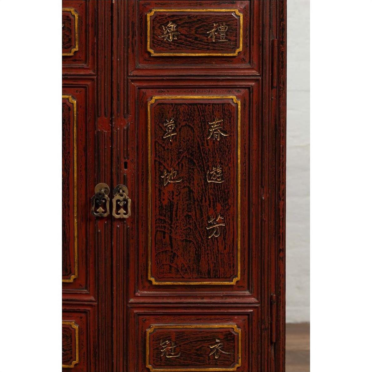 Close-up of red negora lacquer Japanese display cabinet with gilded calligraphy and ornate brass handles.