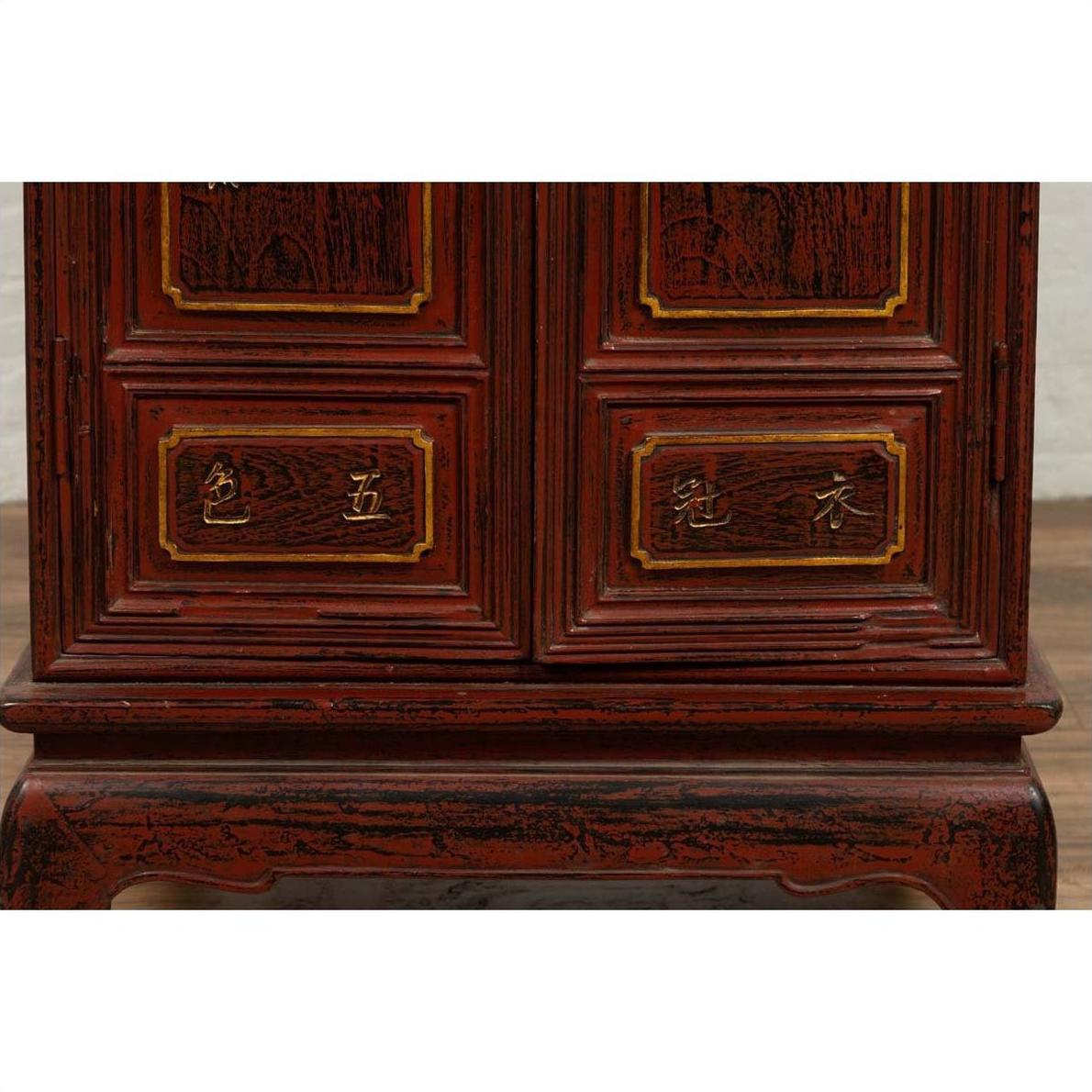 Close-up of red Negora lacquer and gilded calligraphy on Japanese wood display cabinet lower panels.