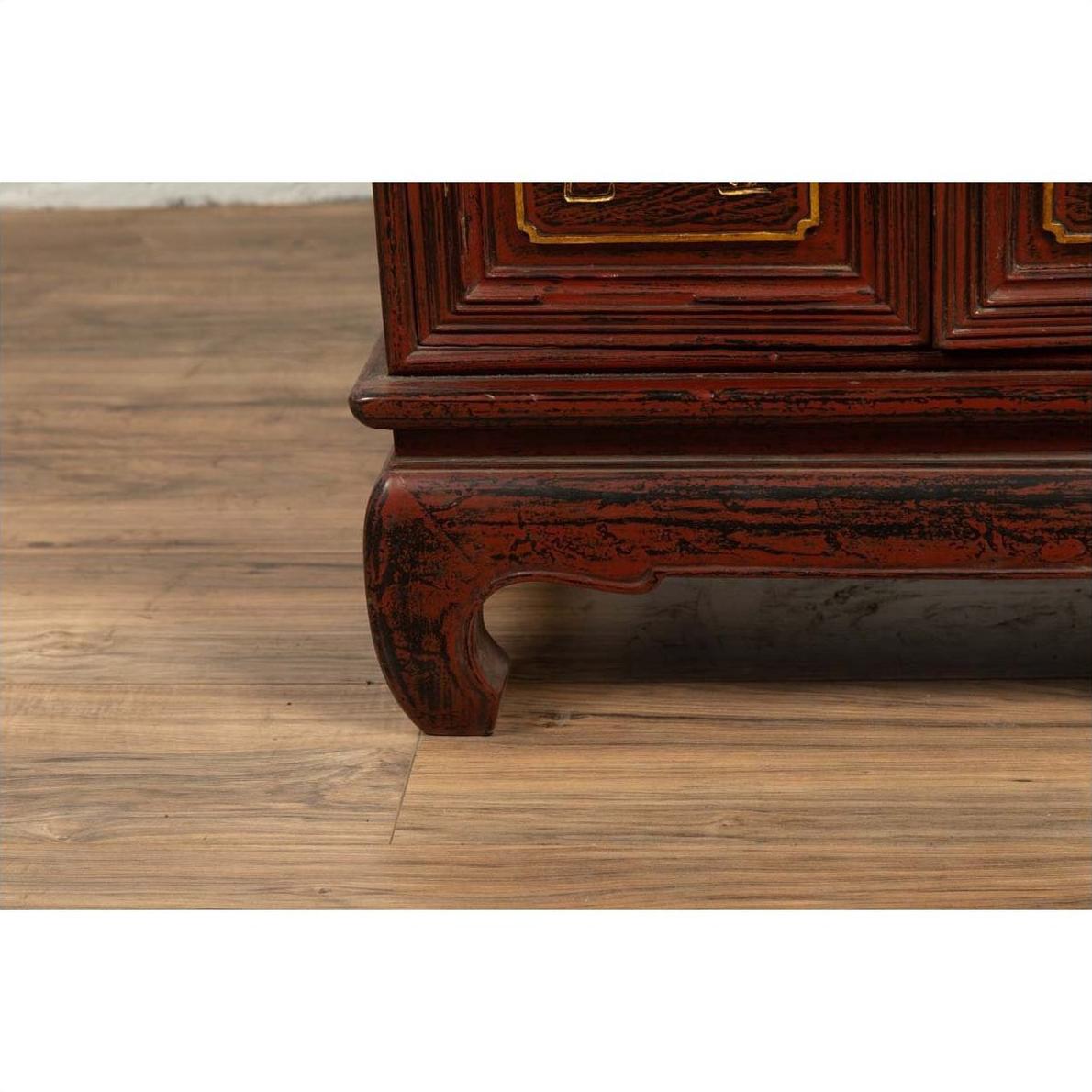 Close-up of red lacquer and gold calligraphy leg on vintage Japanese display cabinet indoors.