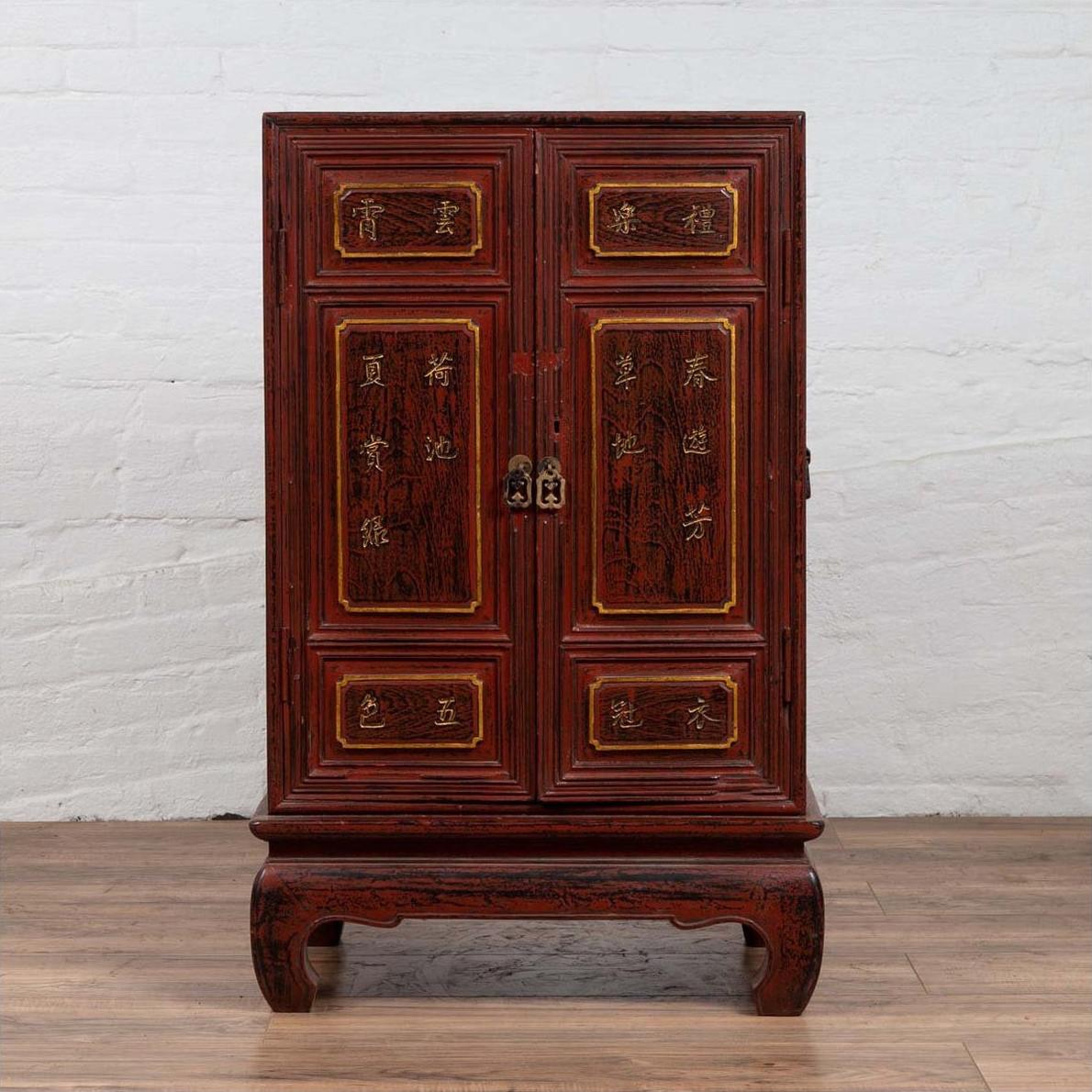 Red Negora lacquer cabinet with gilded calligraphy, short curved-leg base, shown indoors.